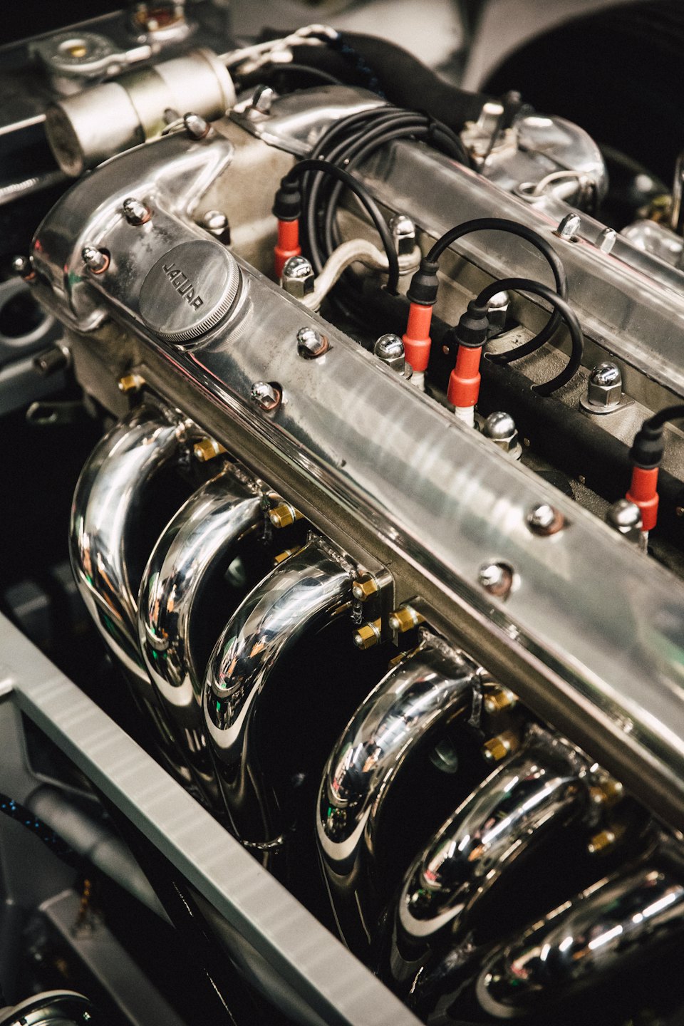 Collettori di scarico cromati lucidi su un motore di auto d'epoca pulito.