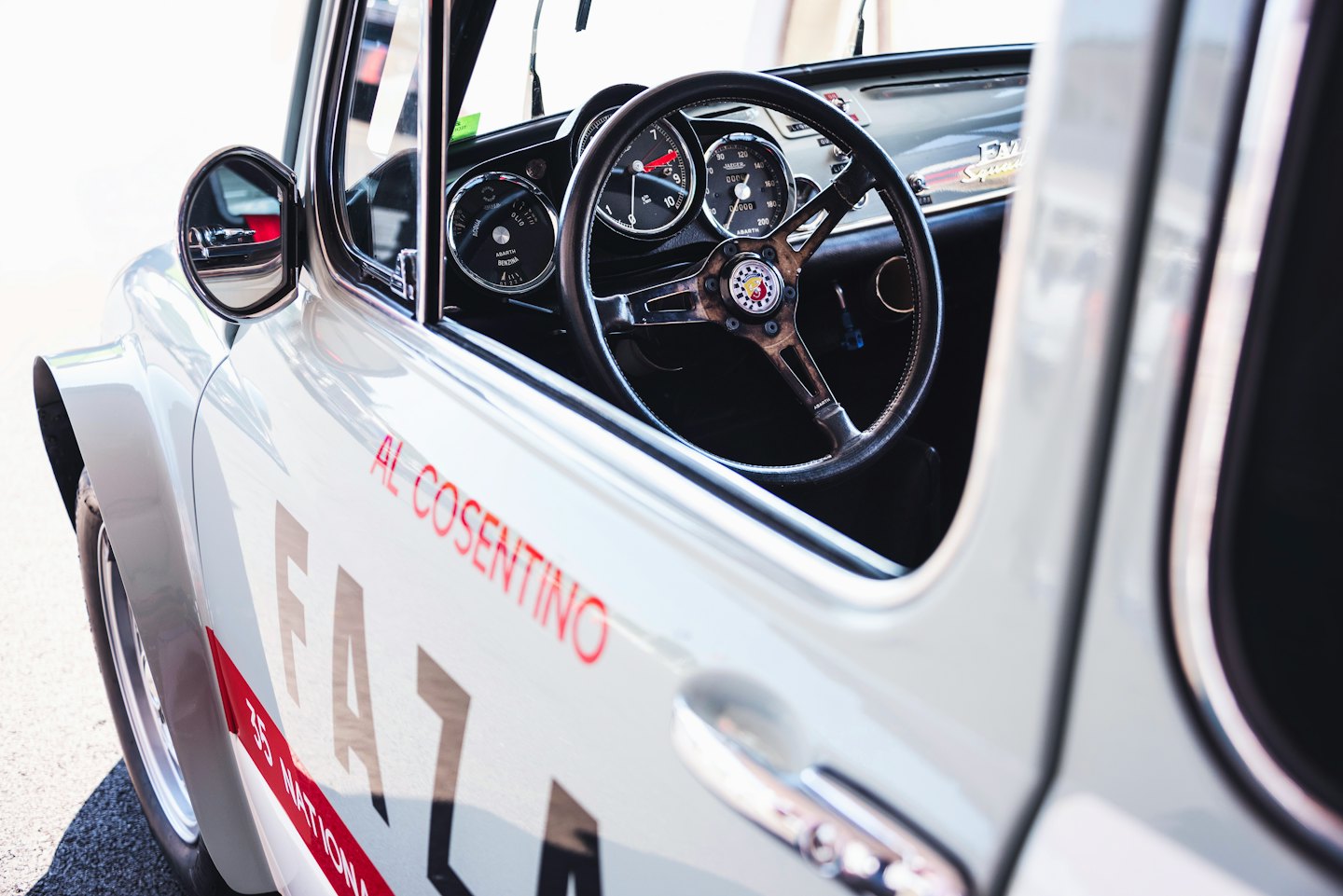 Auto da corsa bianca d'epoca parcheggiata con cruscotto e indicatori visibili.